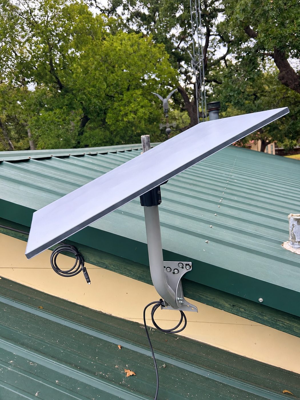 Bracket mount over a standing-seam roof in Grayson County, post oak crowding the far side